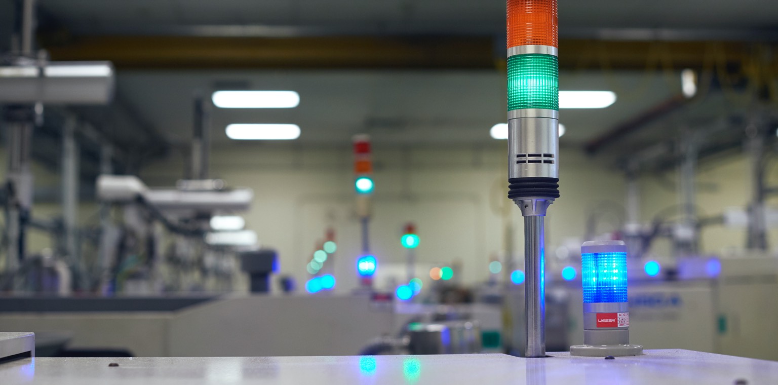 Close up image of a colored indicator light with factory in the background